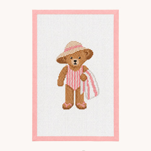 A needlepoint canvas design featuring a brown teddy bear wearing a pink and white striped swimsuit and a pink hat, holding a pink striped towel. The design is framed by a pink border on a white canvas, set against a light beige background with the 'STUDIO daisy' logo at the bottom.